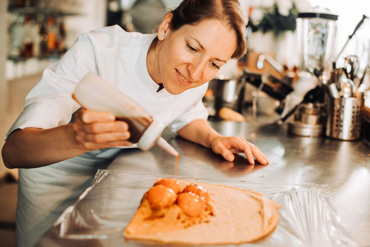 Female chef is adding ingredients to make a dessert