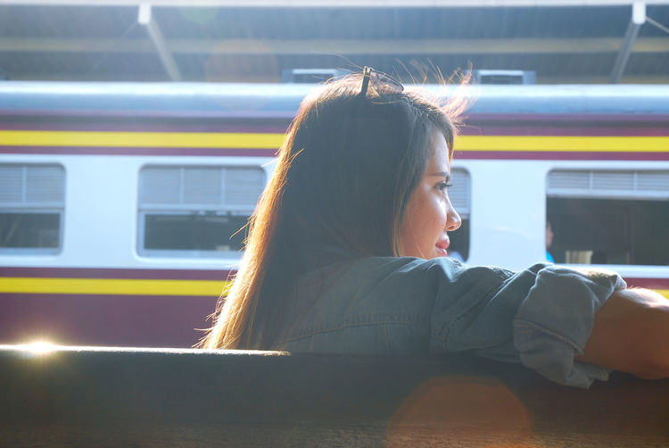 Rear view of young woman sitting on railroad platform