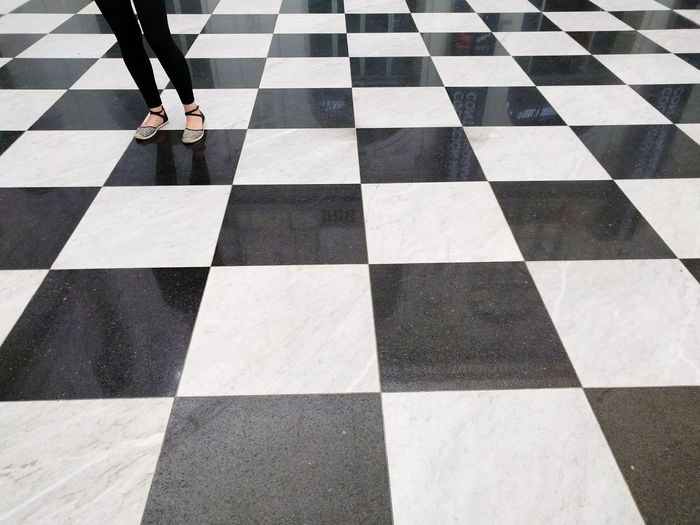 Low section of woman standing on checked pattern floor