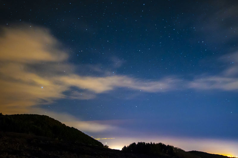 Low angle view of silhouette mountain against sky at night