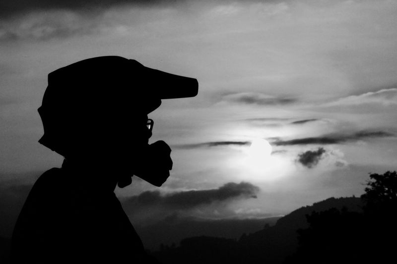 Silhouette person in helmet against sky during sunset