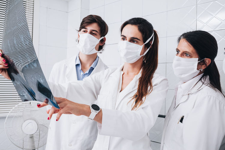 Group of doctors with a mask on their face examining an x-ray in a hospital room