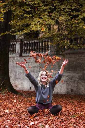 Smiling young woman with autumn leaves in park