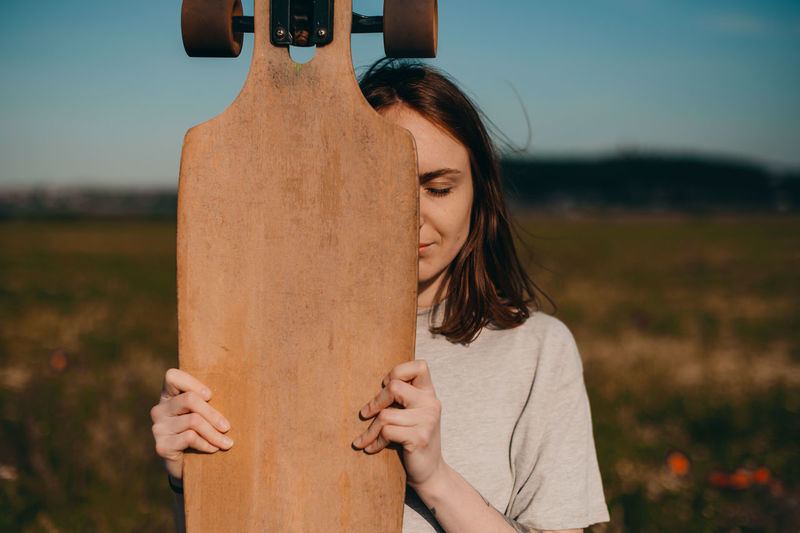 Woman hiding face with skateboard