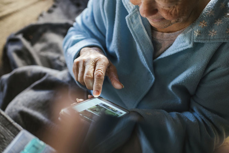 Elderly woman text messaging on smart phone at home