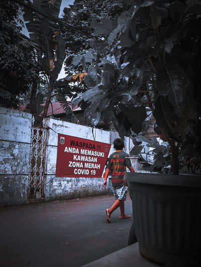 Man with text on street against trees in city