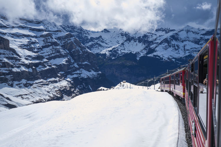 Train on snowcapped mountains against cloudy sky