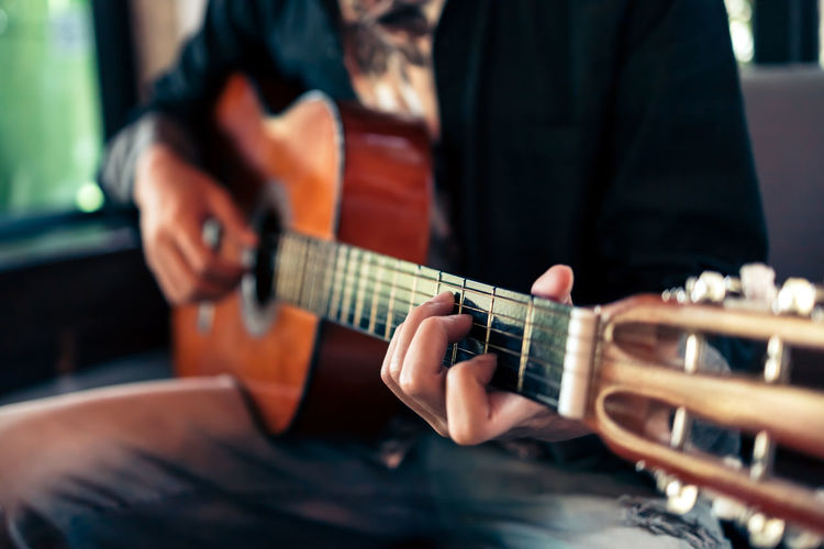 Close-up of man playing guitar indoors