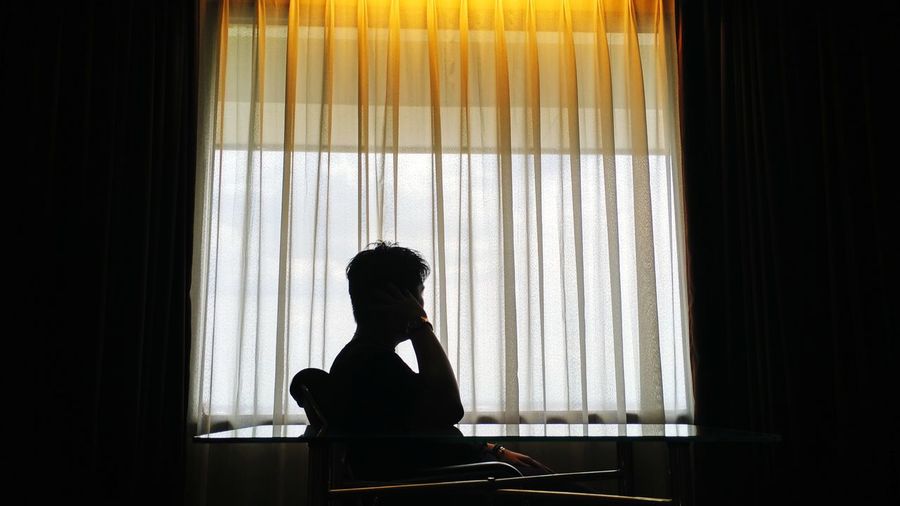 Side view of silhouette man sitting at home