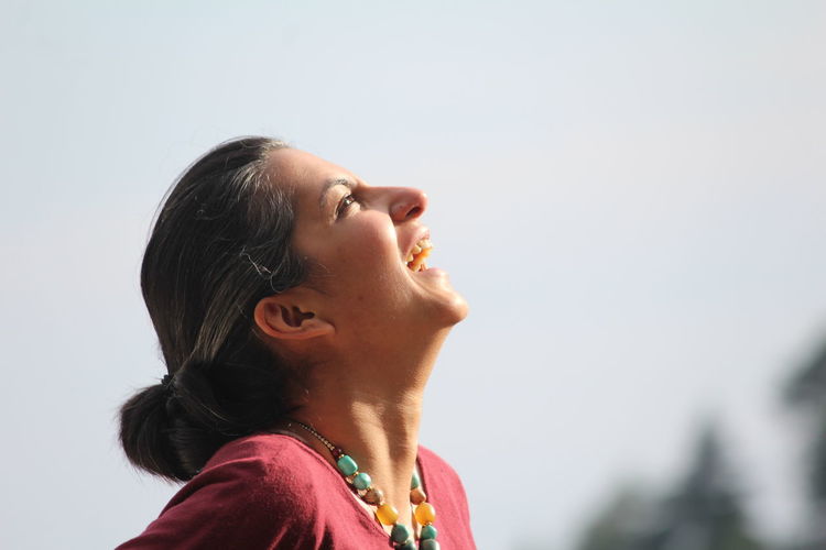 Close-up of woman laughing against clear sky