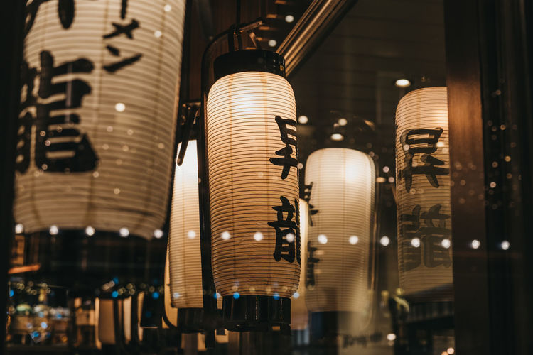 View through the window of the illuminated japanese lanterns inside a restaurant.