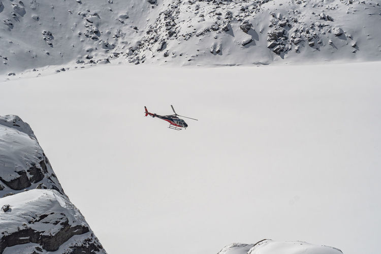 Low angle view of helicopter flying in snowcapped mountains
