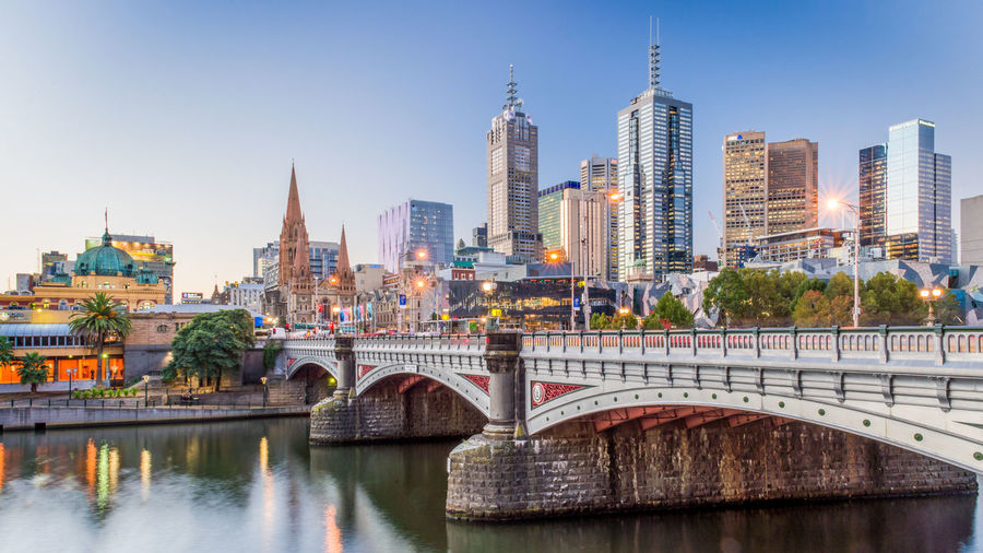 Modern buildings in front of yarra river against clear sky at dusk