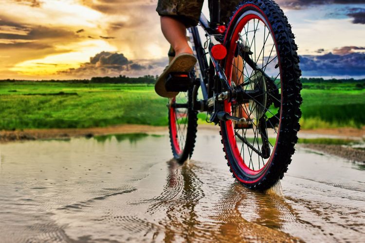 Low section of person riding bicycle on puddle