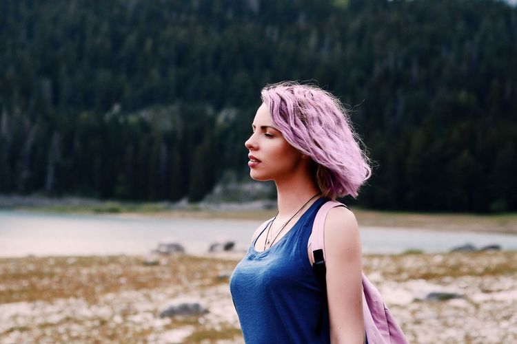 Portrait of a beautiful young woman with pink hair standing on land