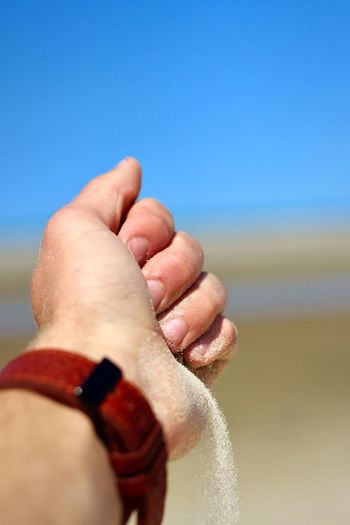 Close-up of hands against sea against clear sky
