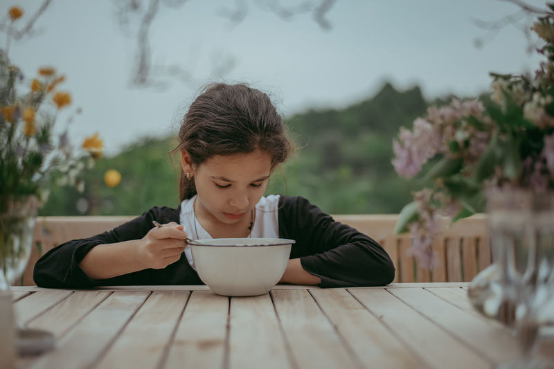 Portrait of girl eating from a bowl on table