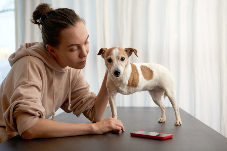 Pet owner supports the three-legged dog sitting at table