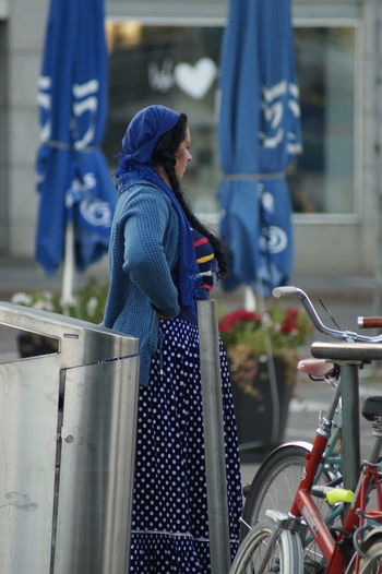 Side view of man and woman standing on bicycle in city