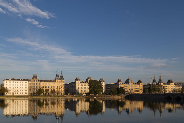 Buildings by river against sky