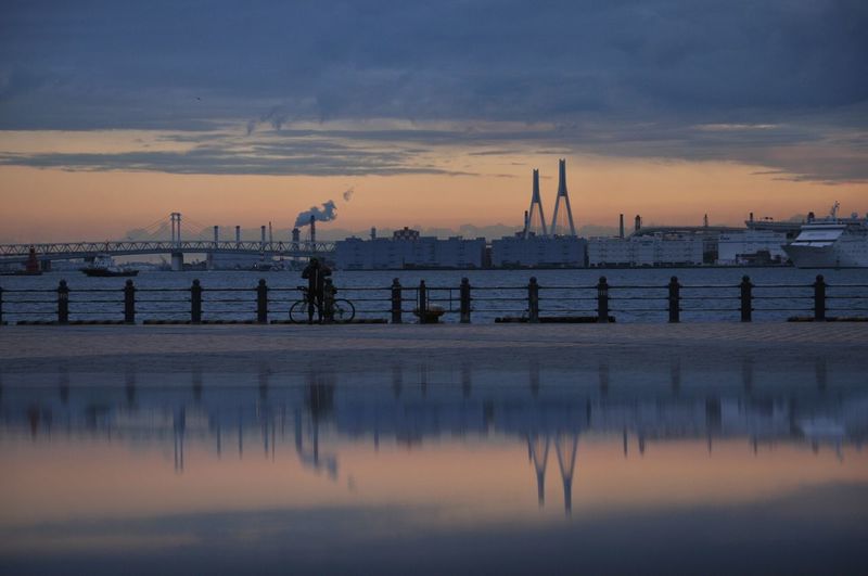 Yokohama bay bridge over sea against cloudy sky during sunrise