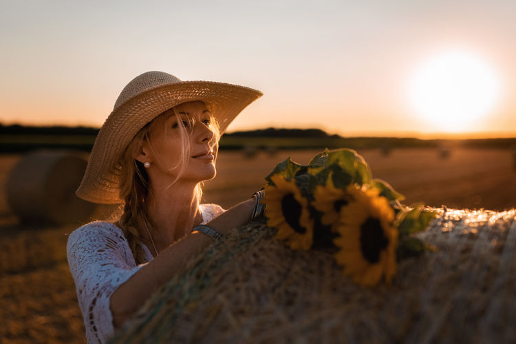 Woman with straw hat on a field during sunset
