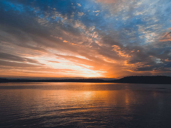 Scenic view of sea against dramatic sky during sunset