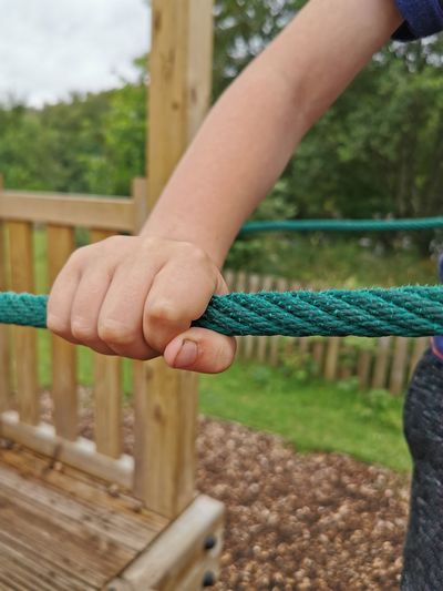 Close-up of hand holding rope on railing