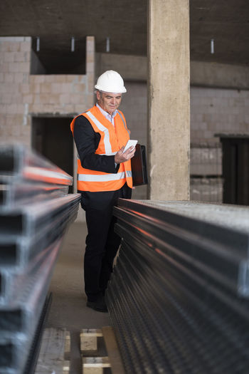 Man with cell phone wearing safety vest in building under construction