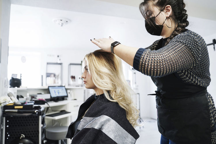 Hairdresser doing hairstyle on customer's hair in salon