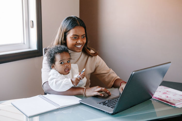 Mixed race indian mother with african black baby working online from home. workplace of freelancer 