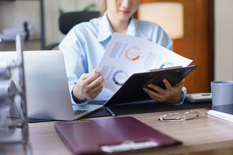 Midsection of woman using laptop at table