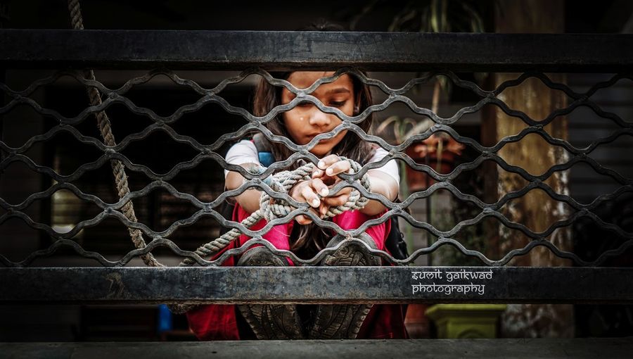 Girl tied with rope on metal railing
