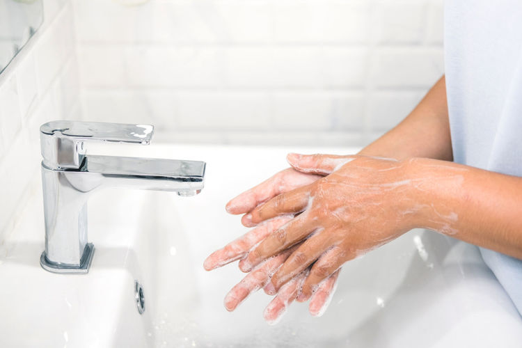Midsection of woman washing hands in sink