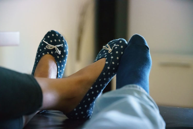 Low section of couple wearing sock at home