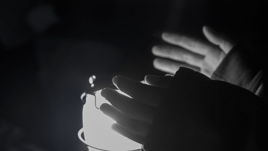 Close-up of hands on illuminated lamp