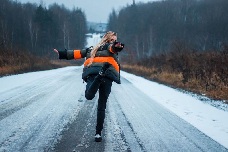 Full length of woman standing on road during winter