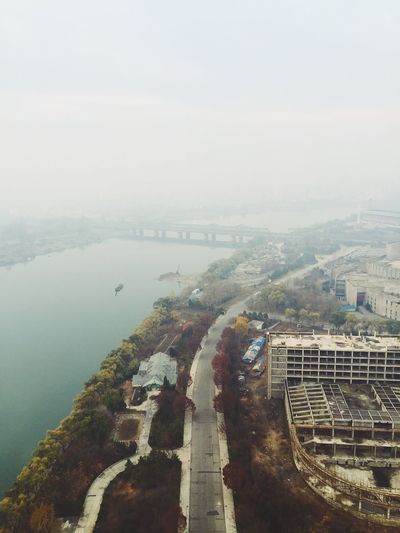 High angle view of road and river against sky in city during foggy weather