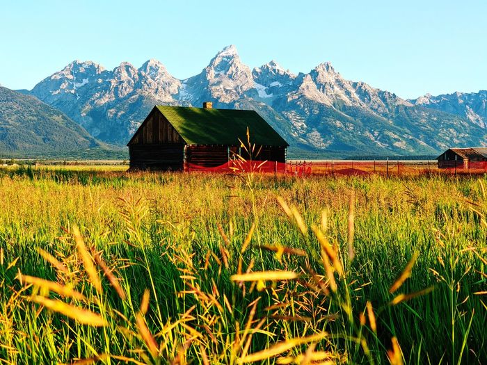 Built structure on field by mountain against sky, grand teton from mormon row district