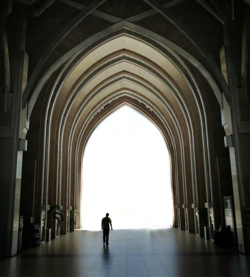 Silhouette man walking in corridor of mosque