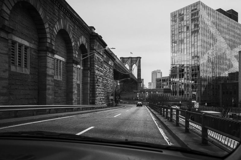 Street amidst buildings seen through car windshield