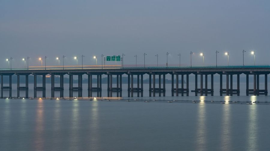 Illuminated pier over sea against clear sky