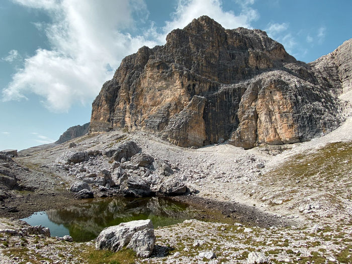 Scenic view of rocky mountains and a lake on sella group near kostner hut against sky, dolomites 