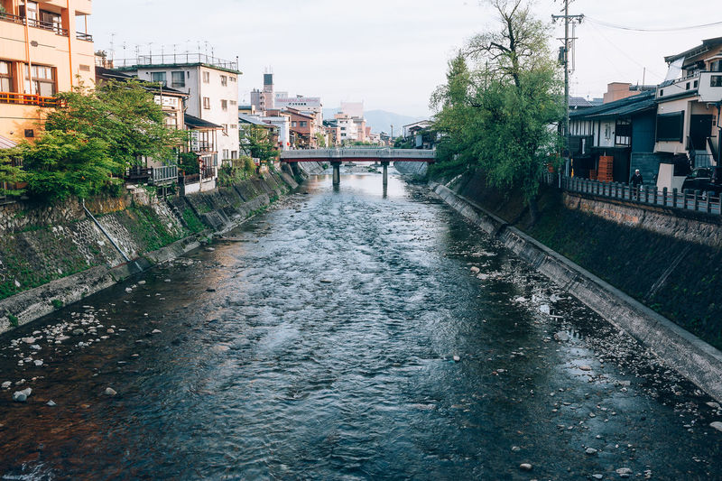 Canal amidst buildings in city against sky