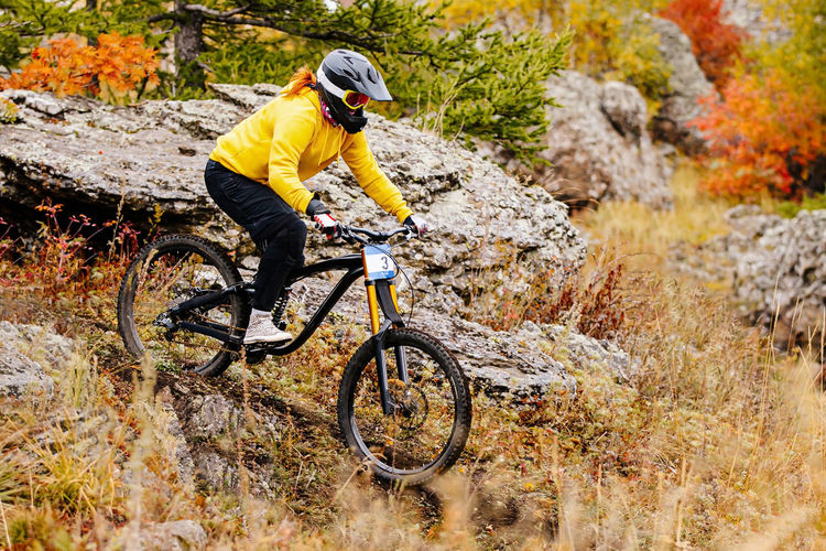 Woman rider riding on autumn trail in downhill race