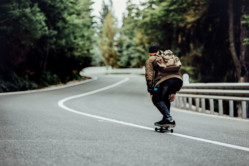 Rear view of man skateboarding on road
