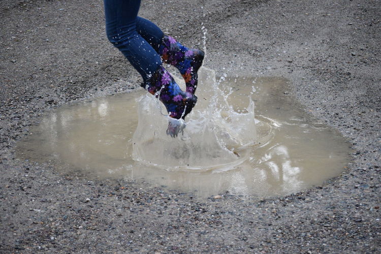 Low section of woman jumping in puddle