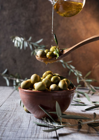 Close-up of oil poured over olives in bowl on table
