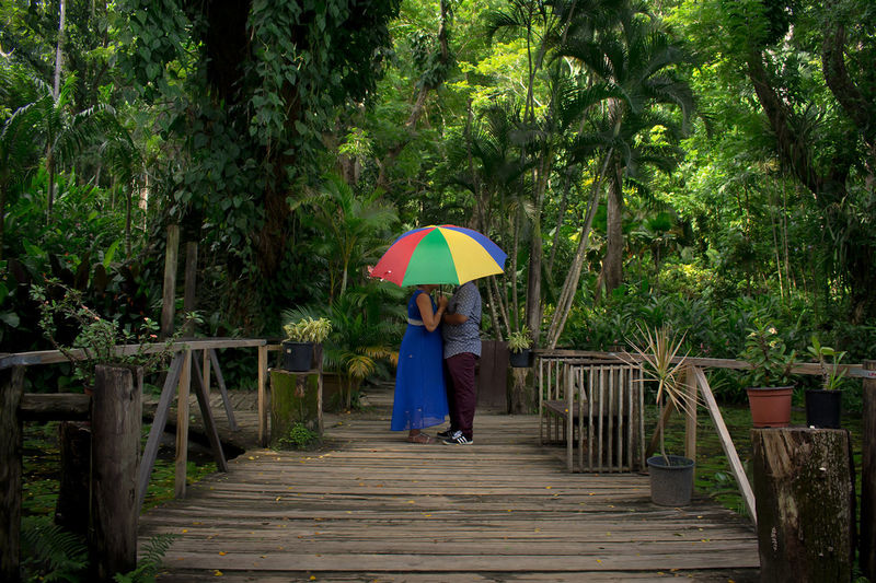 Couple standing below umbrella on boardwalk