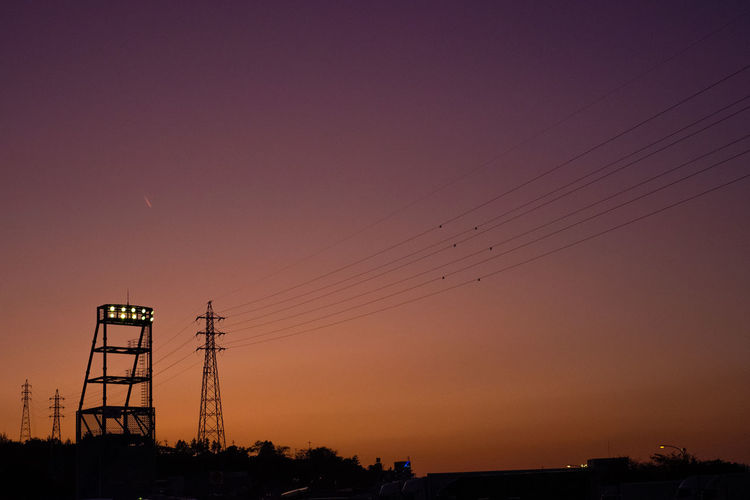 Silhouette electricity pylon against clear sky during sunset